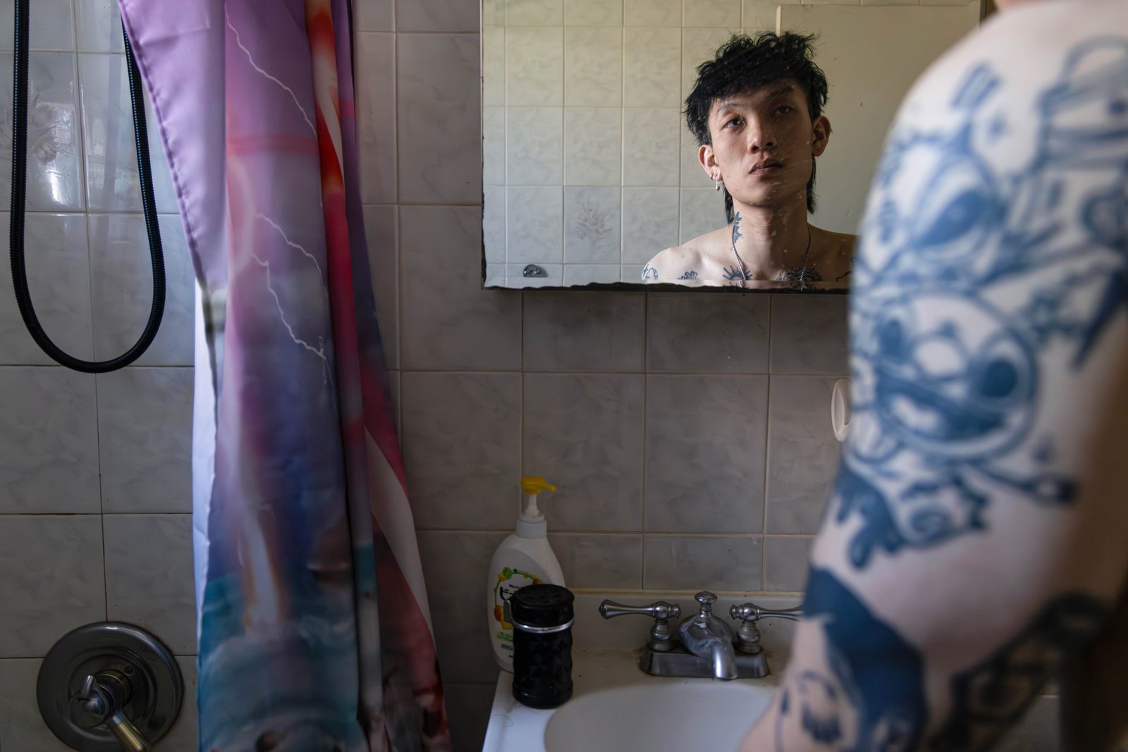 A man’s reflection in a bathroom mirror, a tattooed arm in the foreground — Win or Lose