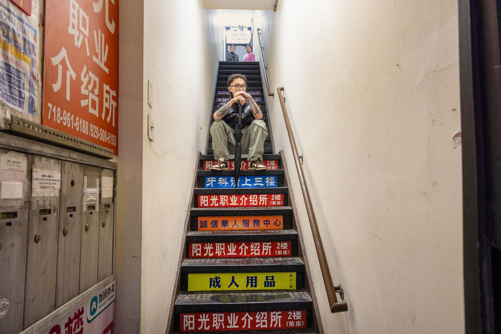 A man seated on a stairway lined with colourful signs — Win or Lose