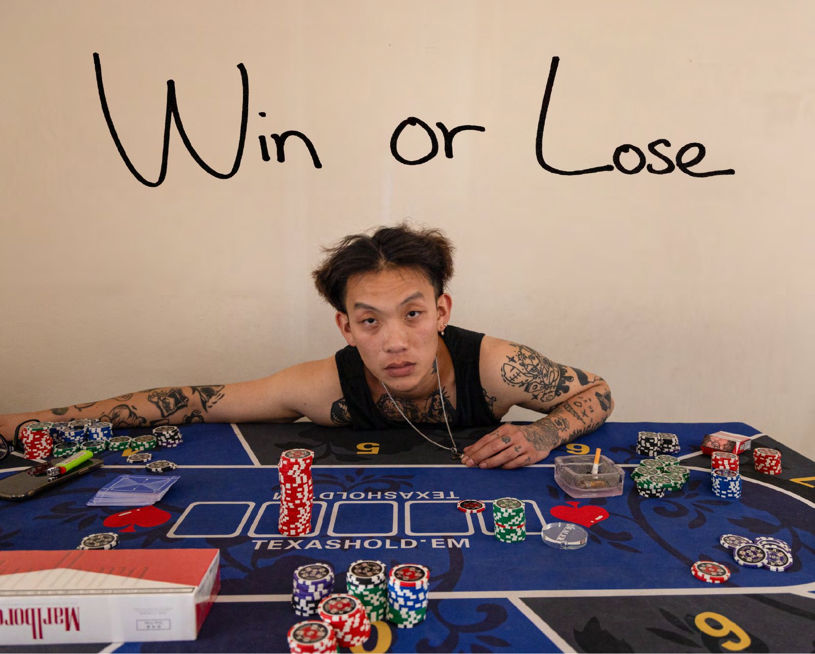 Cover of the Win or Lose photobook — Win leaning over a poker table covered with chips and cards, the title Win or Lose handwritten on the wall above him