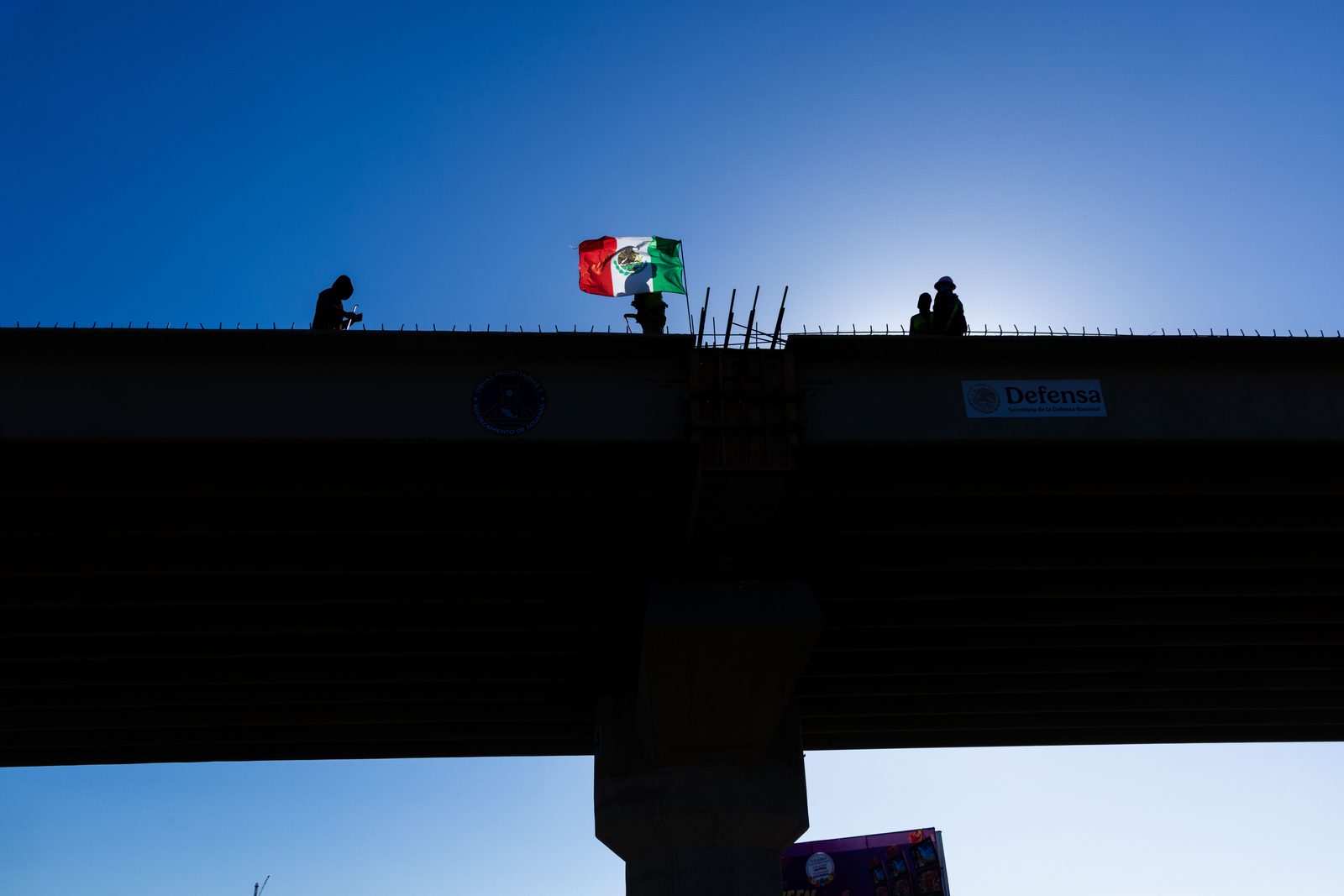 A border wall silhouetted against a clear blue sky — The Liminal Innocence