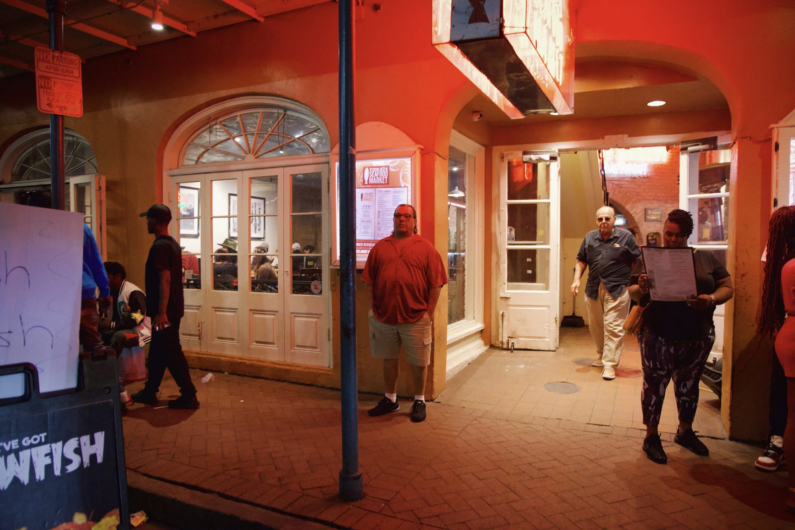 A night street with red-lit shopfronts and figures walking — New Orleans