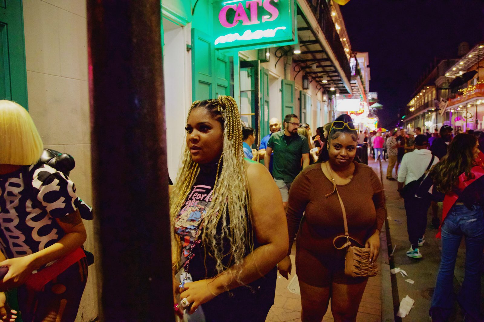 A crowd on a night street, faces lit by shop lights — New Orleans
