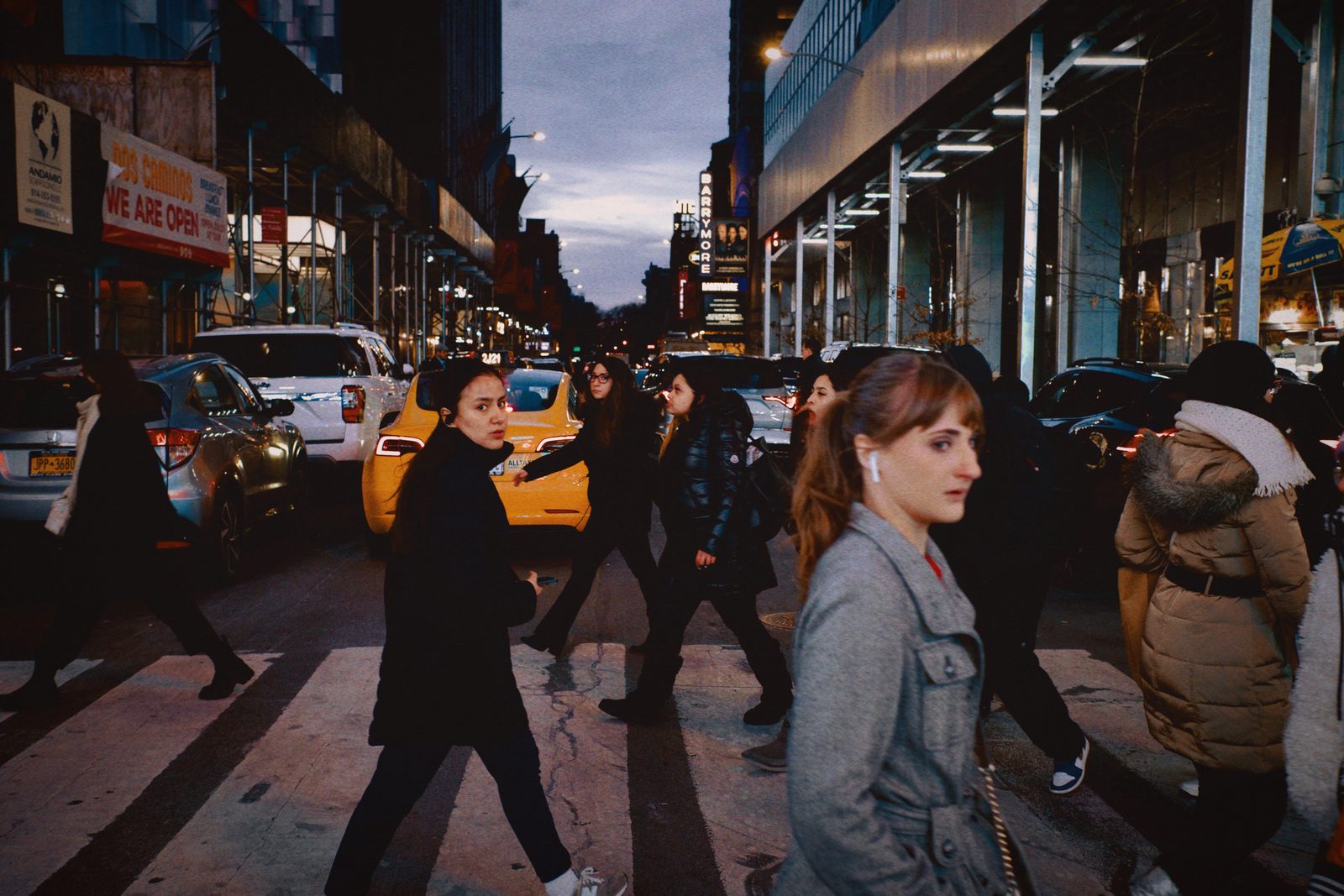 Pedestrians crossing a brightly lit night street — New York