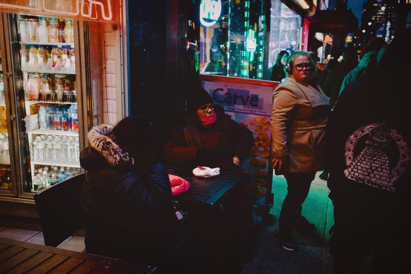 Street vendors and passers-by under bright signs at night — New York