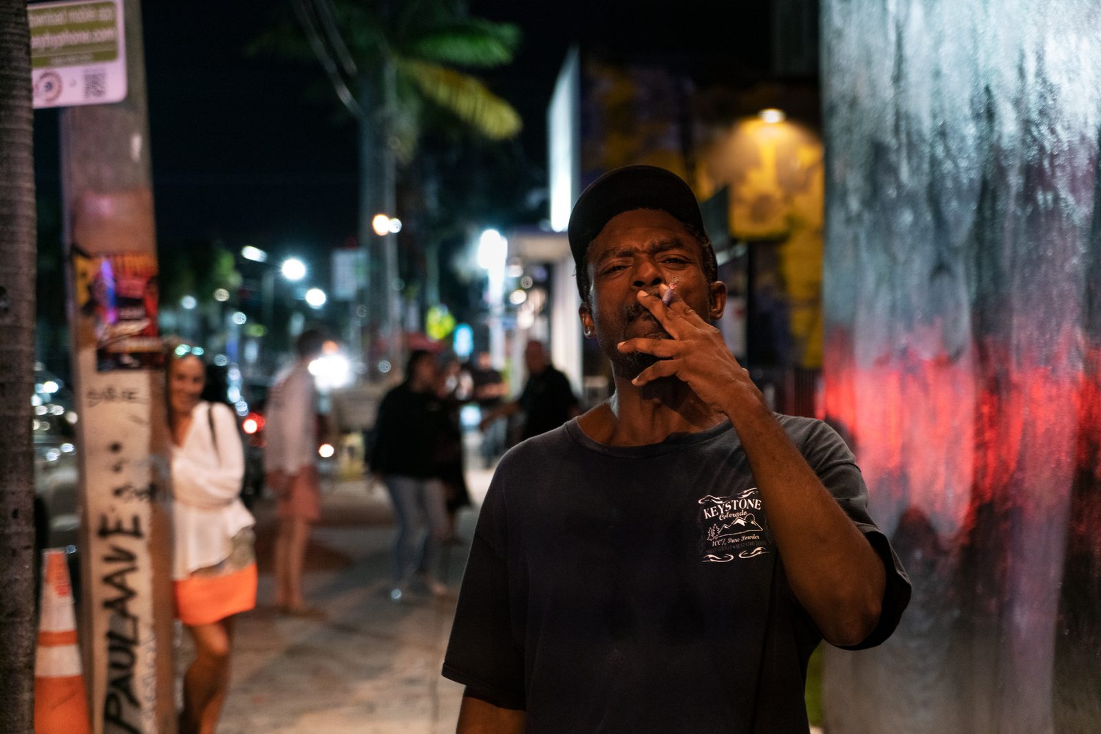 A man talking on a phone on a neon-lit street at night — Miami
