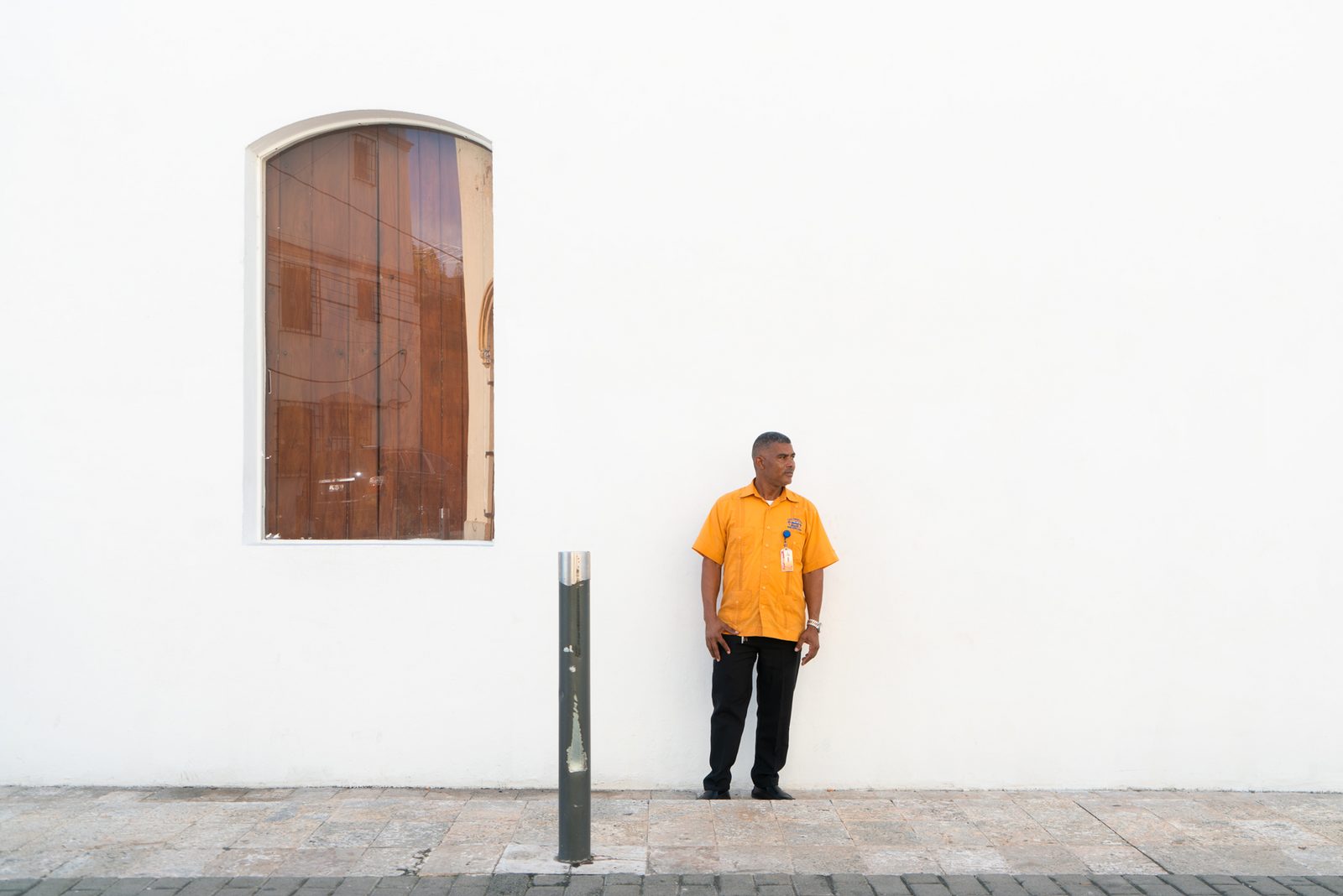 A person in an orange jacket standing against a white wall — Punta Cana