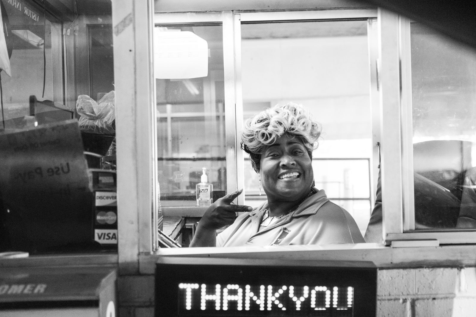 Black-and-white view of a man at a service window above a lit Thank You sign — Chapel Hill