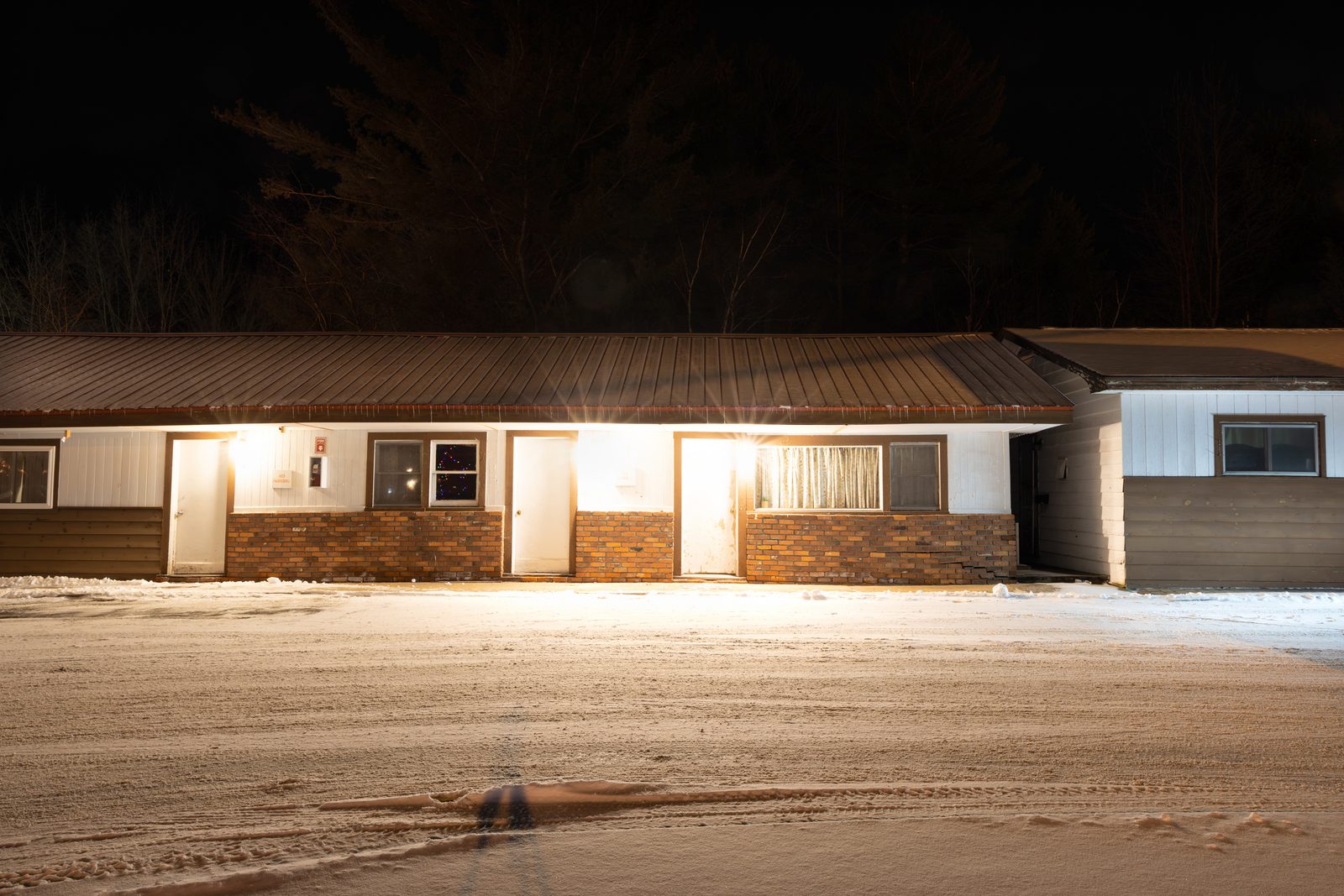 A low motel lit against the night, snow covering the ground in front — Lake Placid